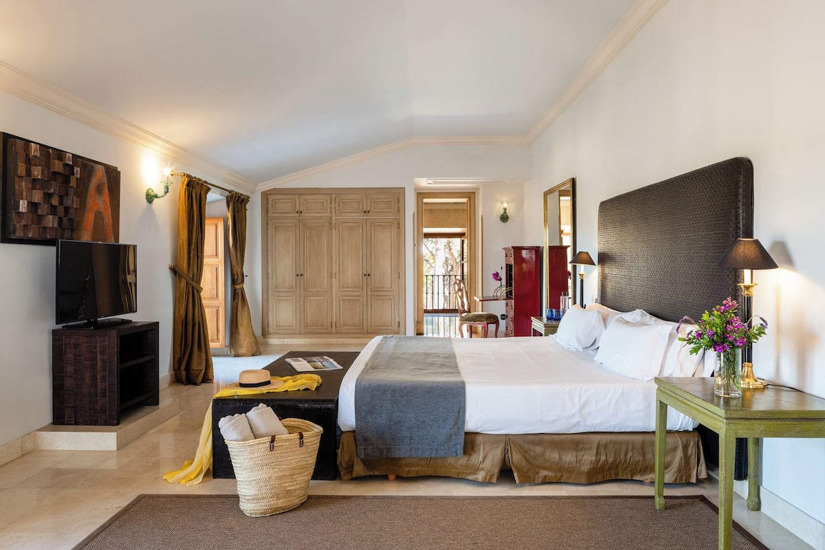 Ein Hotelzimmer mit Bett, Fernseher, Schreibtisch und großem Kleiderschrank.