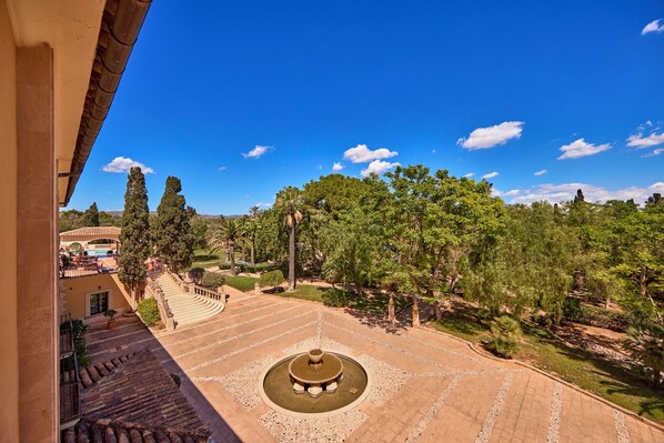 Un patio central con una fuente, rodeado de árboles y un edificio con techo de tejas.