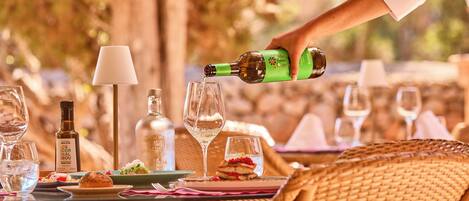 A dining table with a bottle being poured into a glass, surrounded by various dishes and glasses.