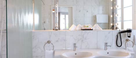 A bathroom with two sinks, a mirror with lights, and a towel rack.