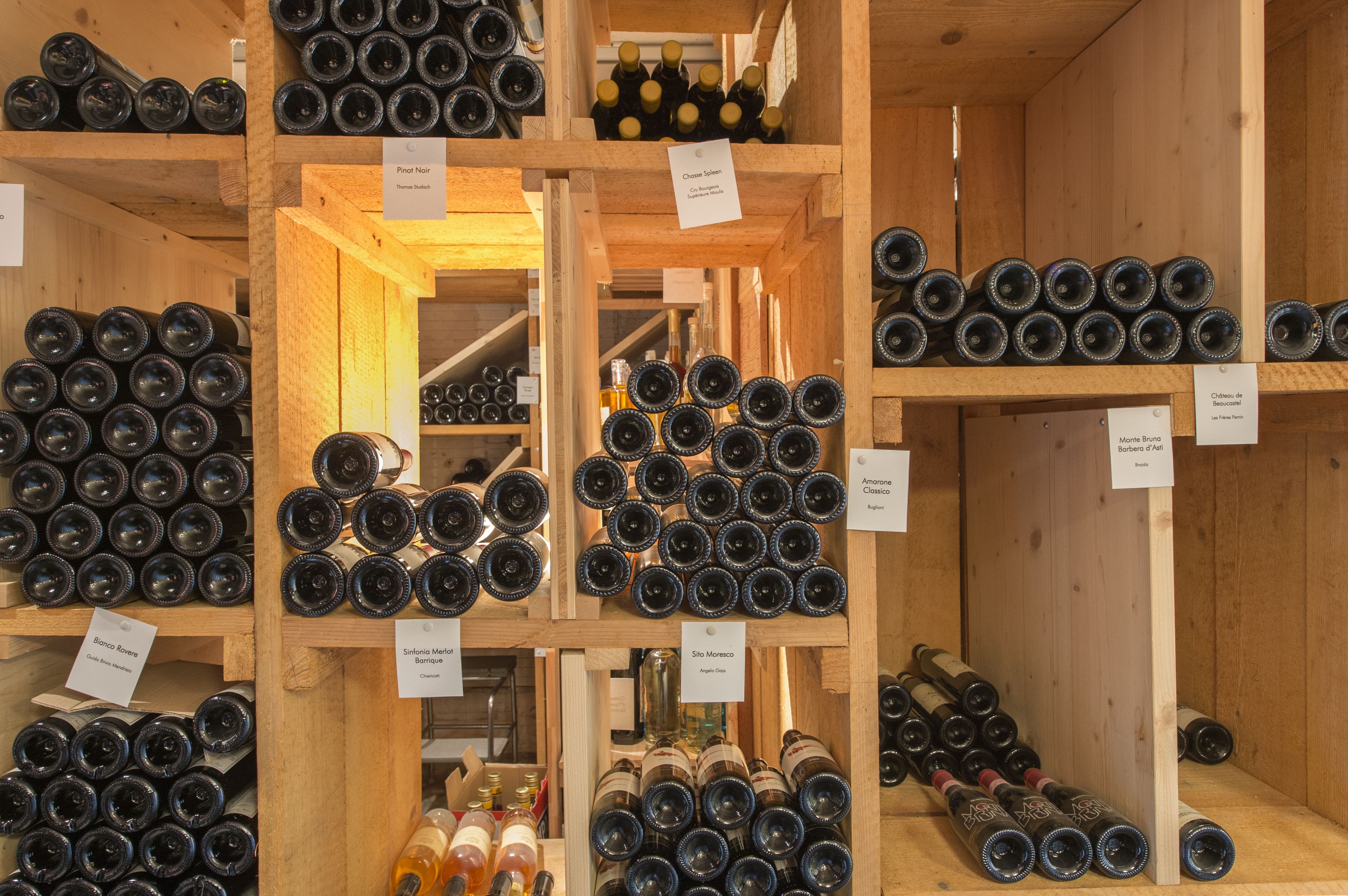 A wine cellar with wooden shelves holding various wine bottles.