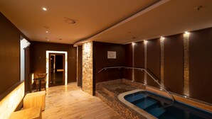 Un área de spa con un jacuzzi, suelo de madera y un espacio de estar con una mesa y sillas.