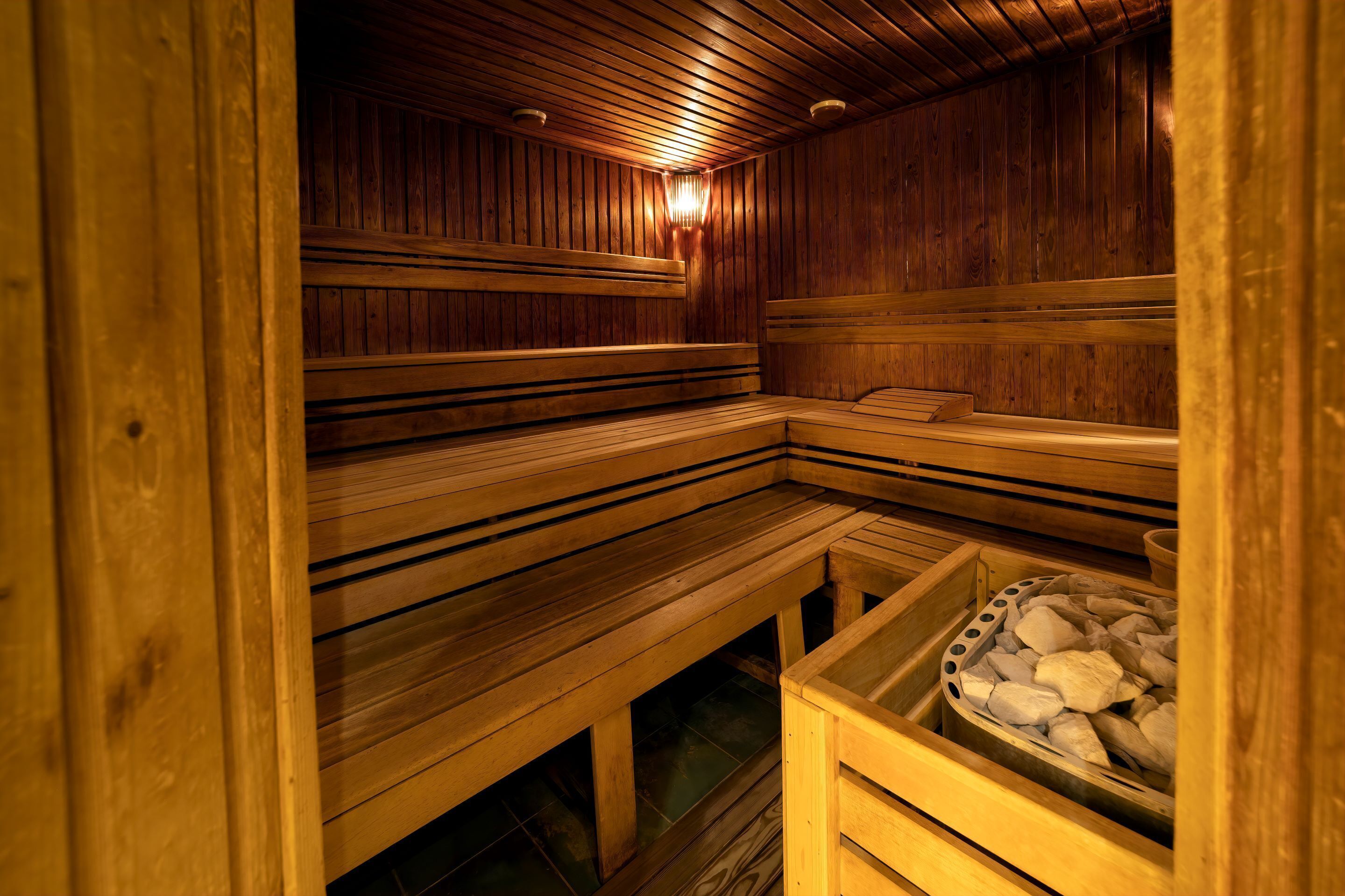 Una sauna con bancos de madera y un recipiente lleno de piedras.