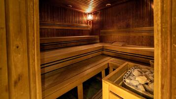 Una sauna con bancos de madera y un recipiente lleno de piedras.