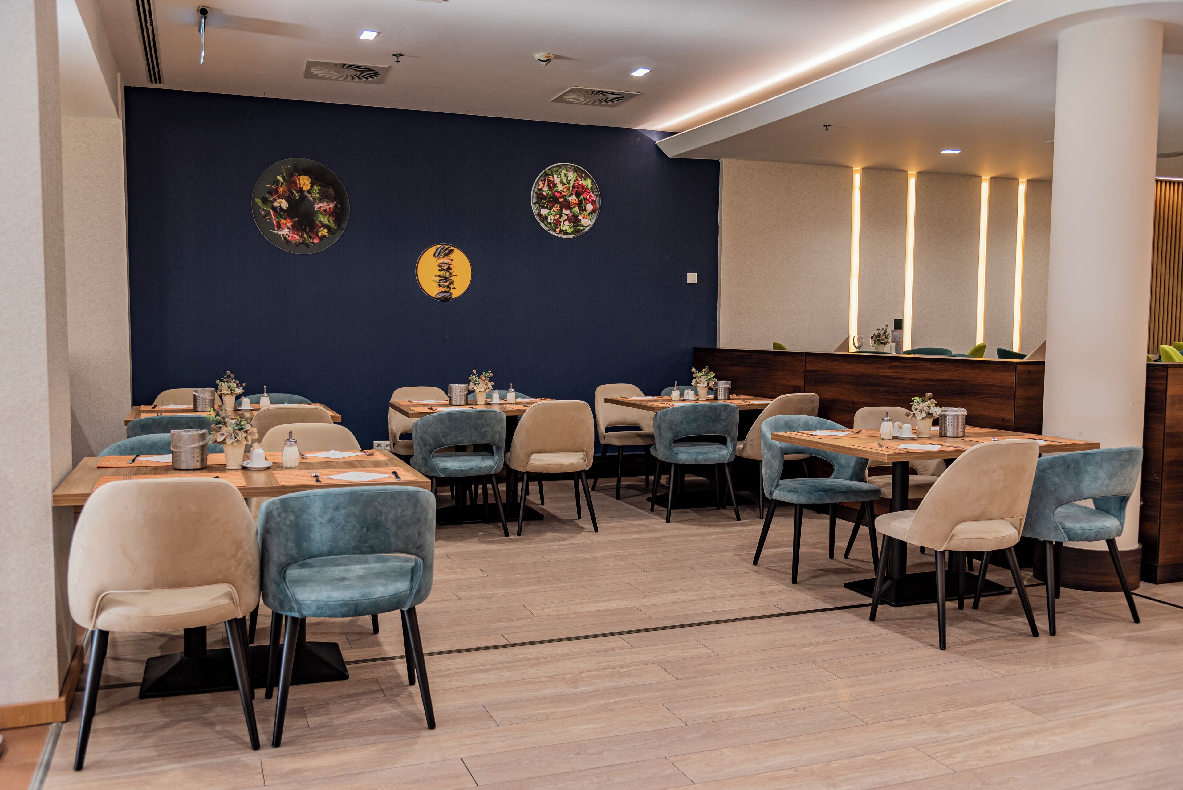 Un restaurante con varias mesas y sillas, una barra con caja registradora y decoración en las paredes.