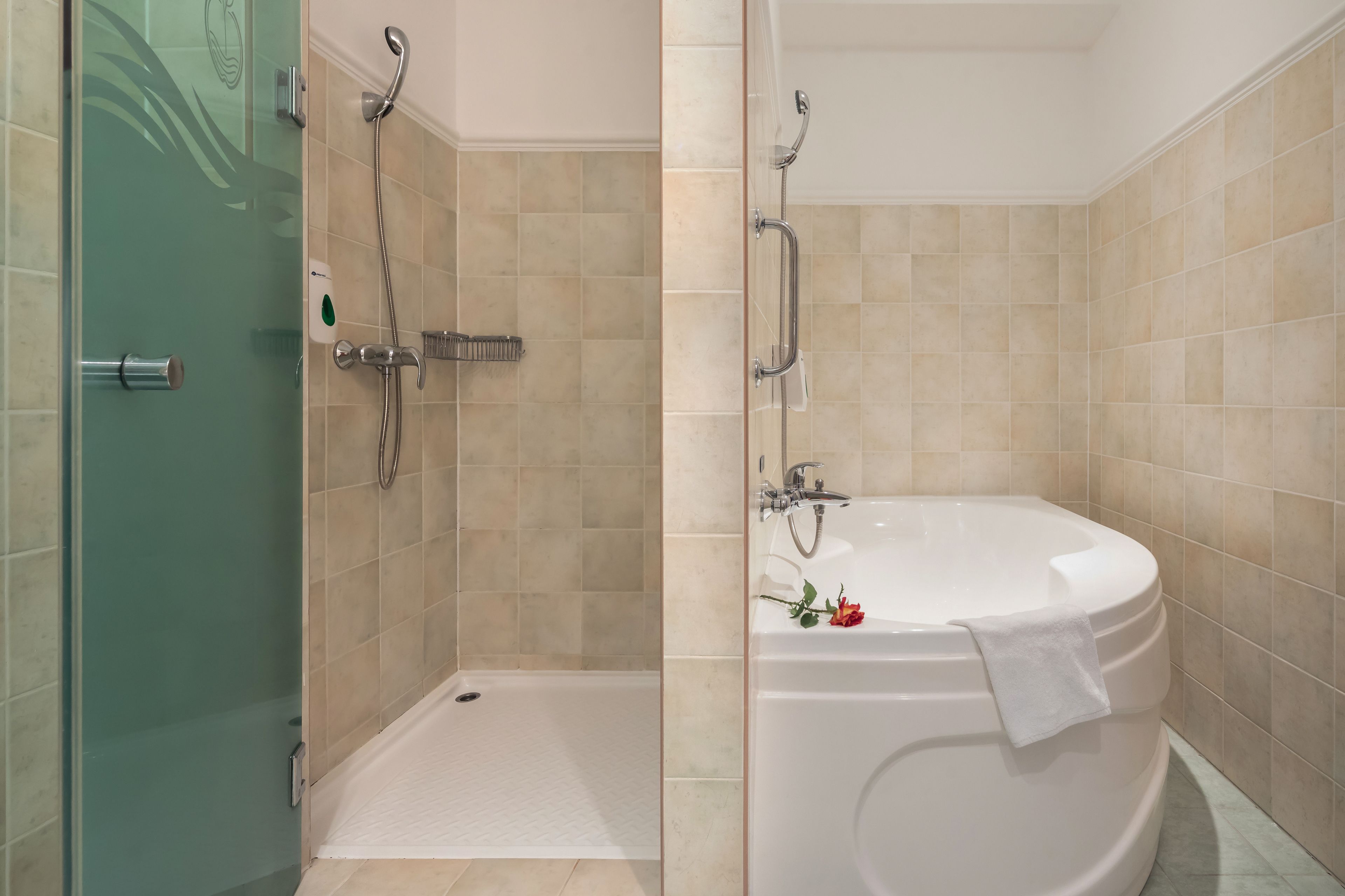 A modern bathroom with a glass shower enclosure, a walk-in bathtub, and beige tiled walls.
