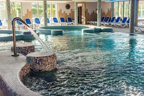 An indoor swimming pool with tiled steps and lounge chairs. - Hotel Karos Spa (Zalakaros)