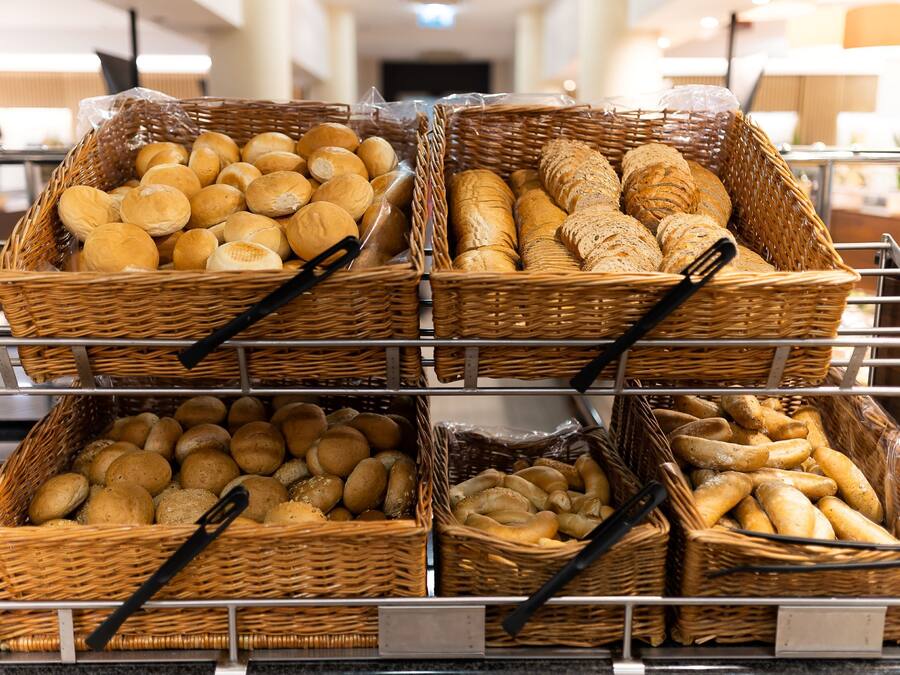 Wicker baskets filled with various types of bread on a metal rack.