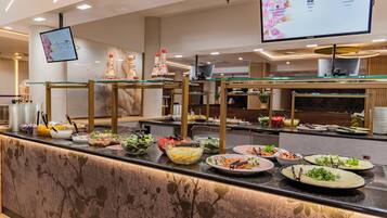Zona de bufé con diversas opciones de comida y una pantalla digital con el menú.