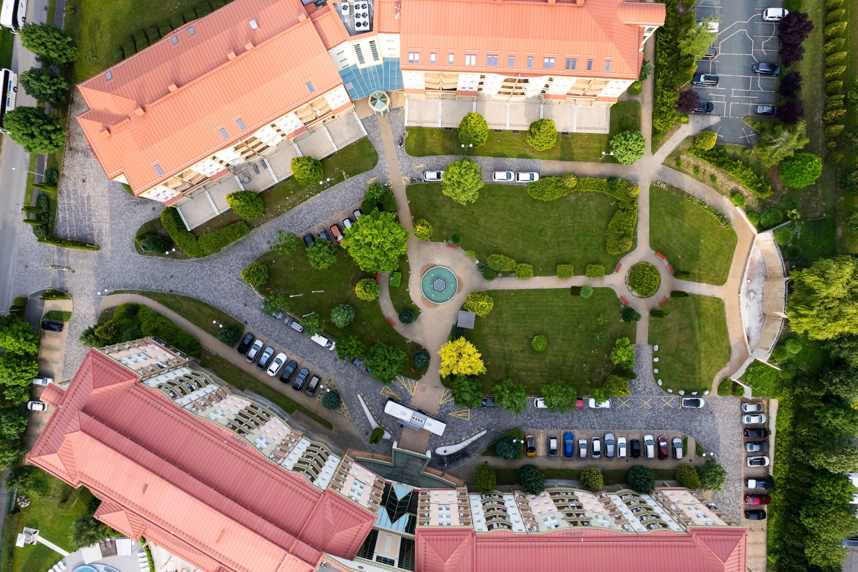 An aerial view of a hotel complex with multiple buildings, parking areas, and landscaped gardens.