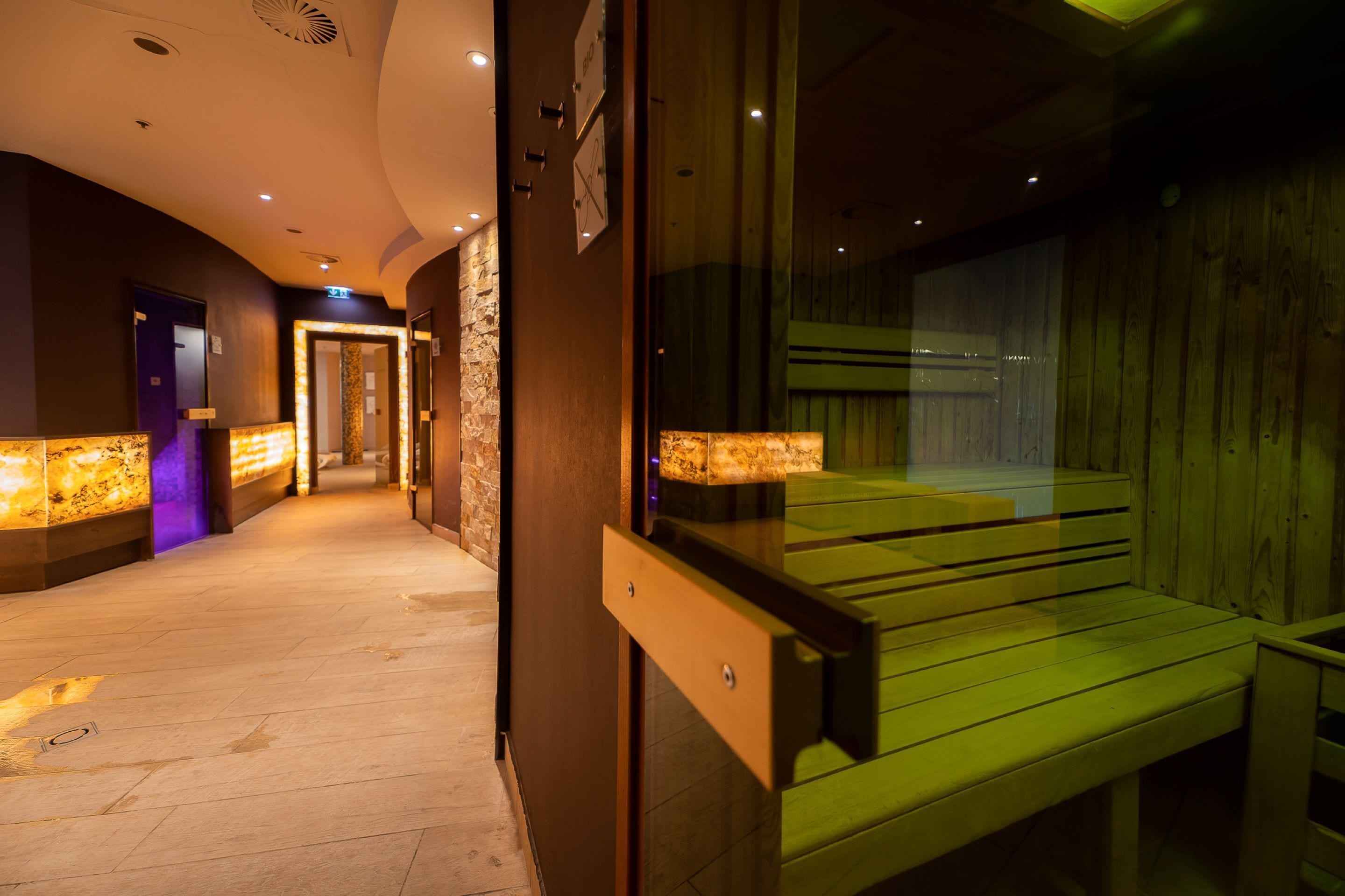 A hallway with a wooden bench, stone walls, and illuminated panels.