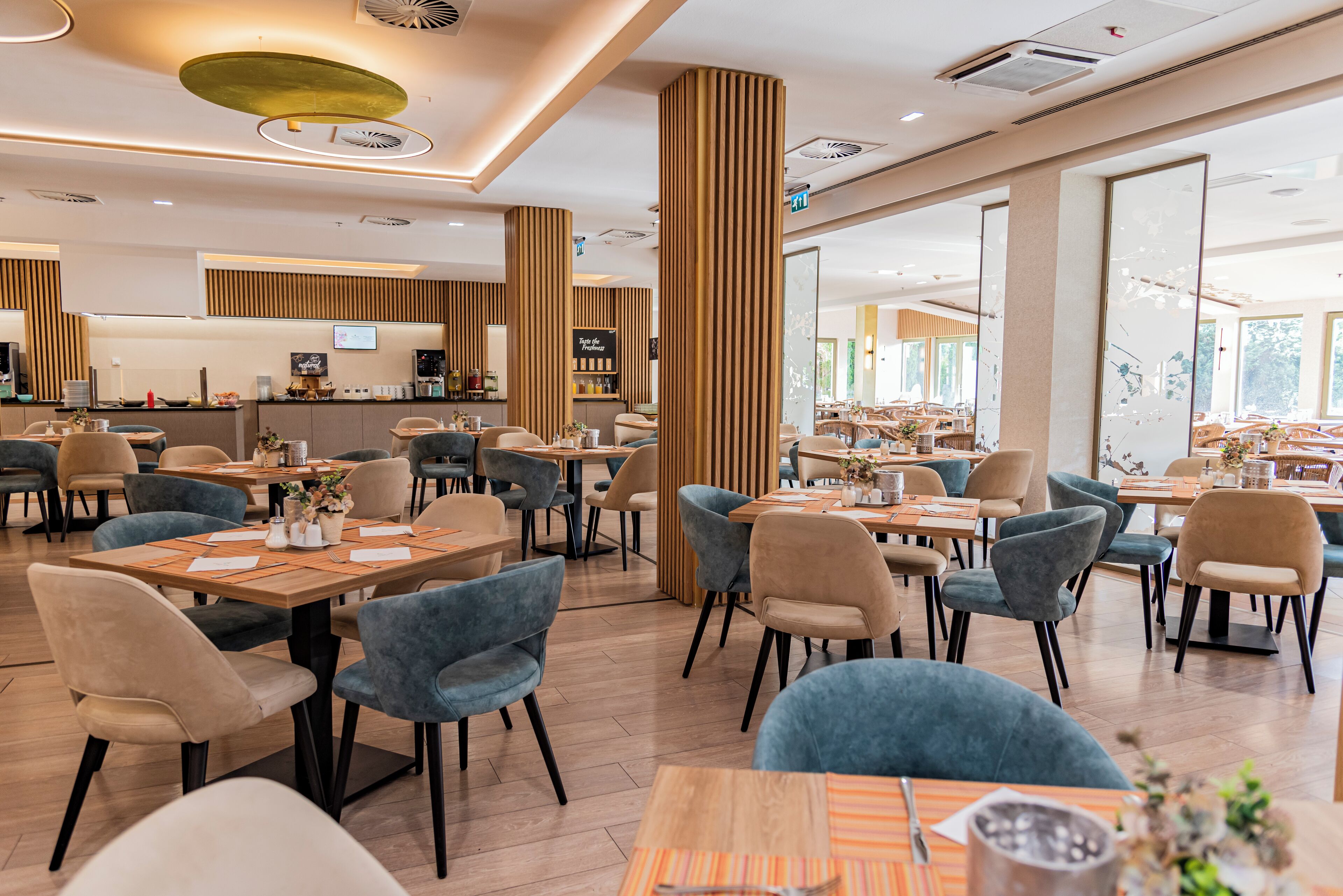 En moderne restaurant med trædetaljer, flere spiseområder og en synlig bar.