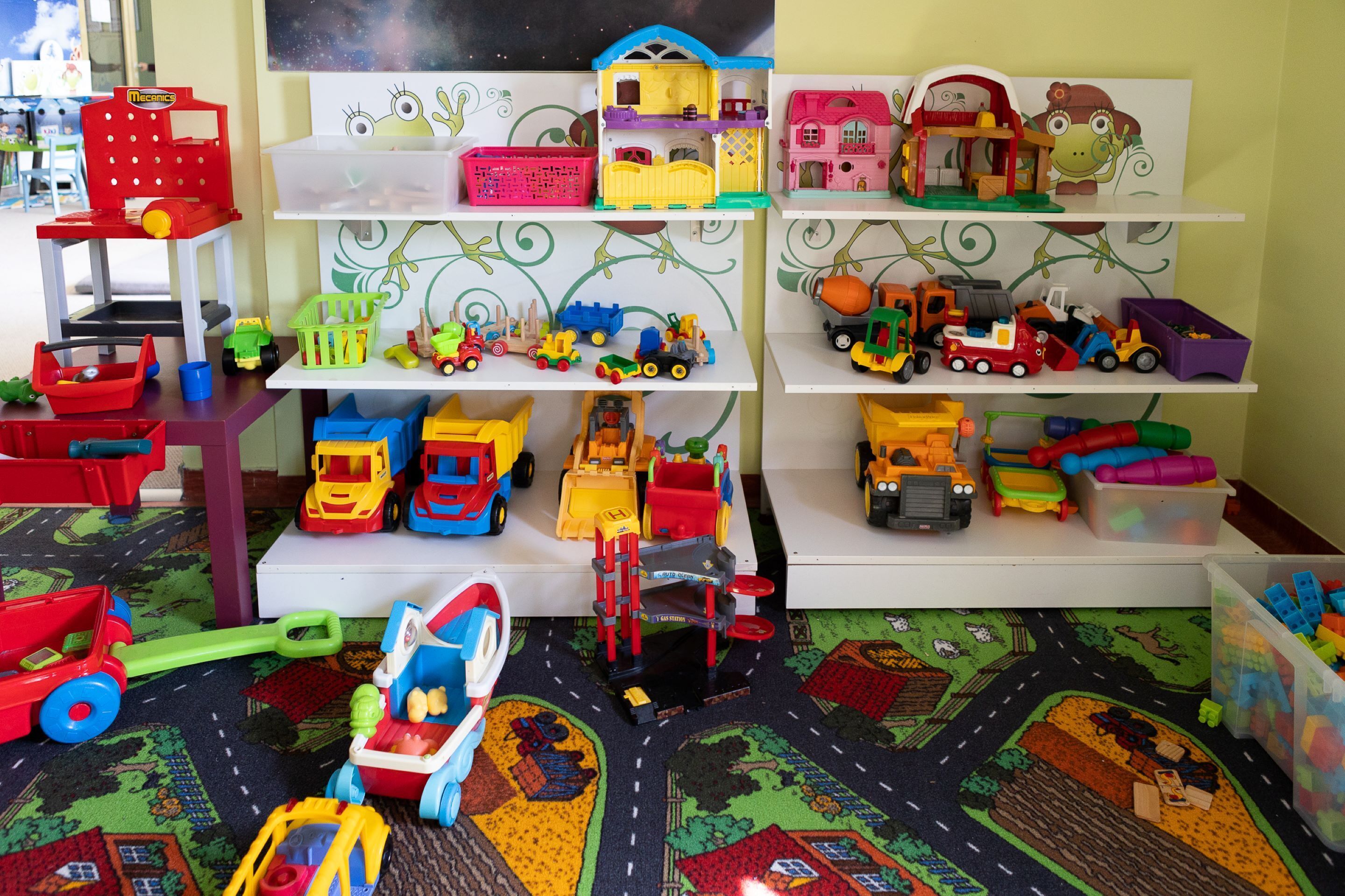 A play area with toy vehicles and buildings on shelves.