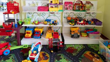 A play area with toy vehicles and buildings on shelves.