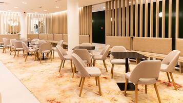 A modern restaurant with booths and tables, a patterned carpet, and a decorative wall with vertical panels.