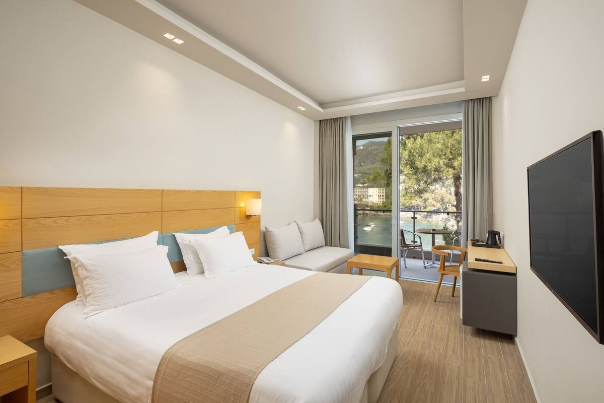 Une chambre d’hôtel avec un grand lit, un bureau, une chaise et un téléviseur.