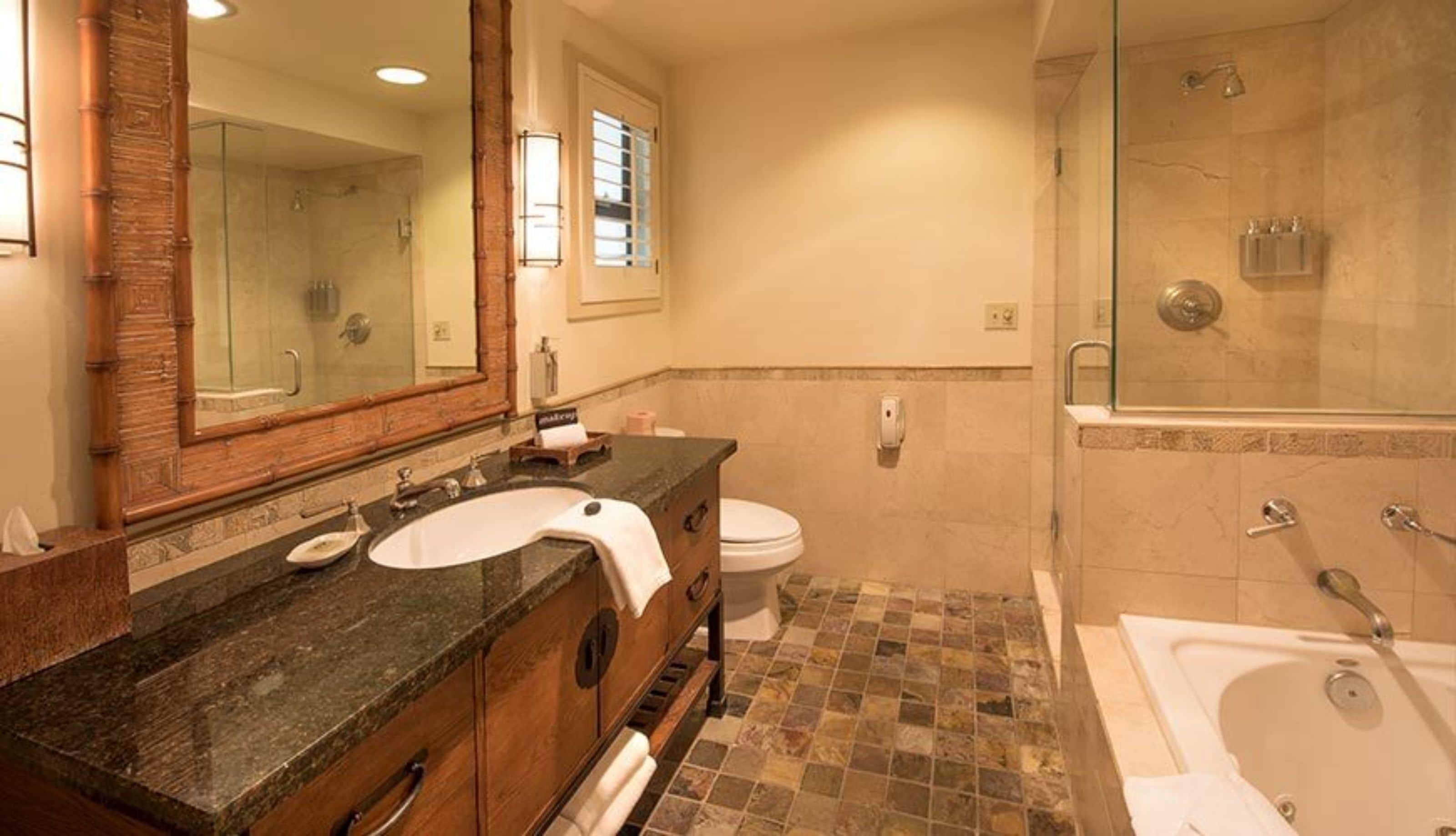 A bathroom with a marble sink, a large mirror, a toilet, and a glass-enclosed shower area.