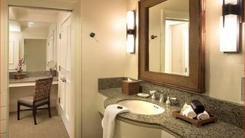 A bathroom with a sink, mirror, towel, and toiletries.