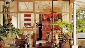 A traditional Japanese-style entrance with sliding doors, stone lion statues, and potted plants. - Tradewinds Carmel (Carmel)