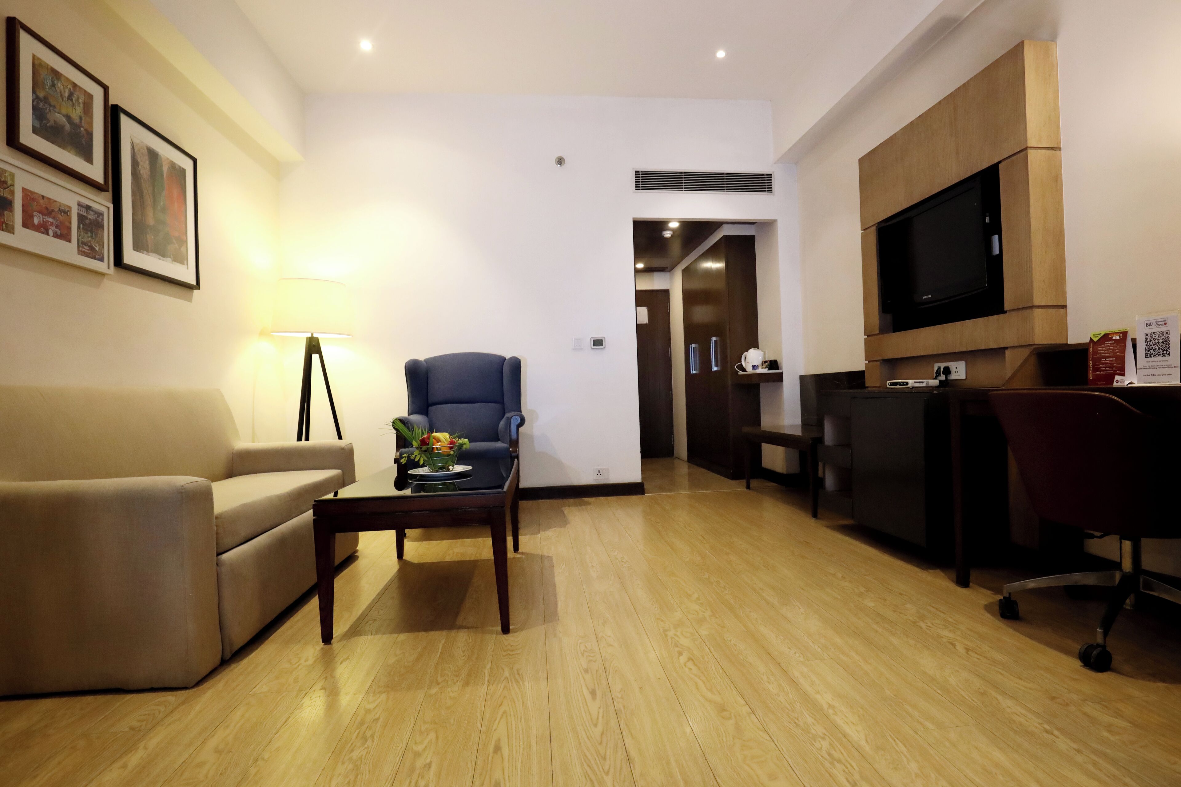 Una sala de estar moderna con un sofá, un sillón, una mesa de centro y un televisor instalado en la pared.