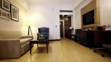 Una sala de estar moderna con un sofá, un sillón, una mesa de centro y un televisor instalado en la pared.