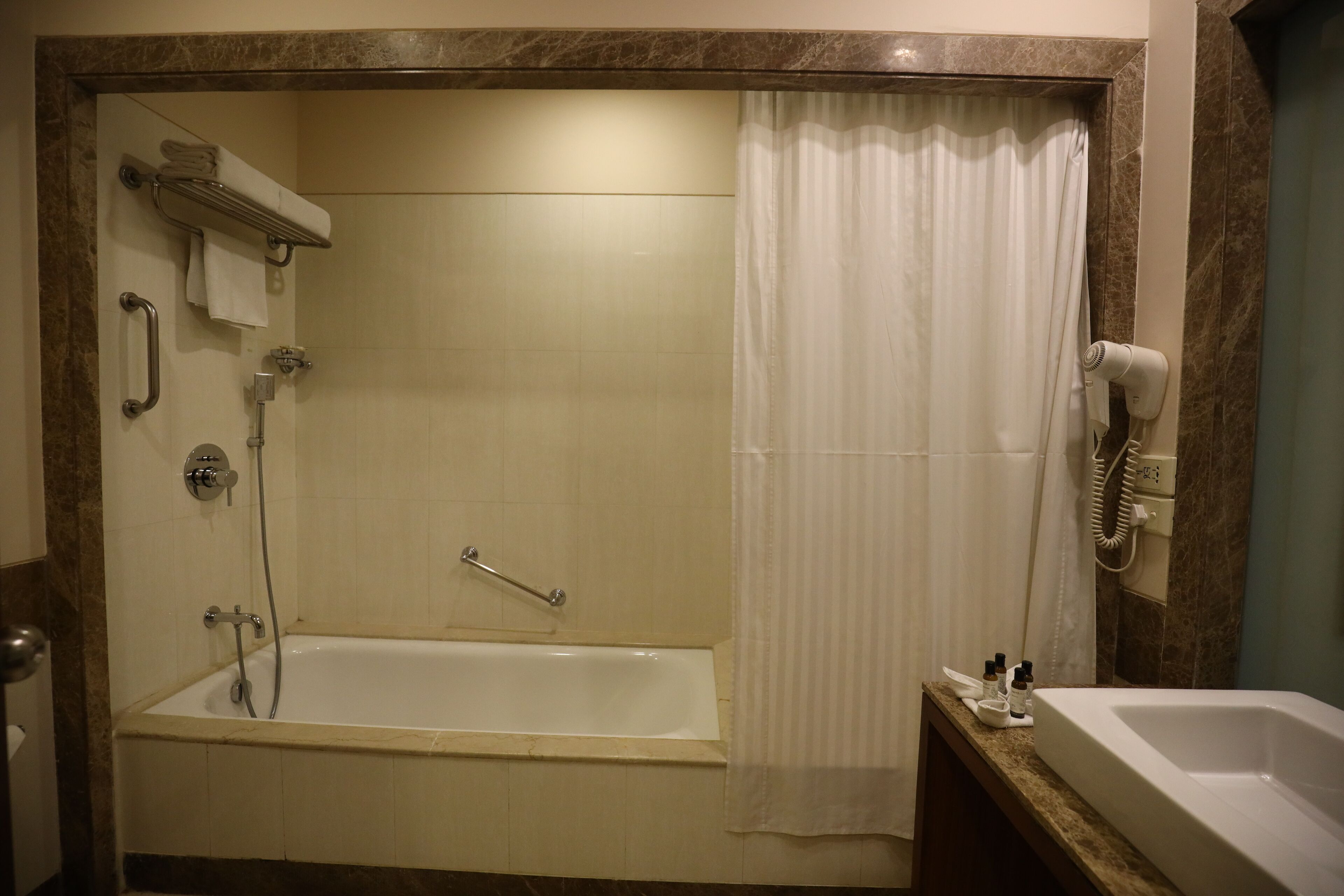 A bathroom with a bathtub, shower, and a hairdryer on the wall.