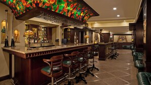 Een bar met een toonbank, meerdere krukken en een decoratief plafond.