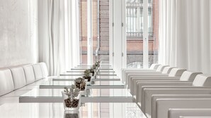 A modern dining area with a long table and white upholstered benches. - The Pure, a Member of Design Hotels (Frankfurt)