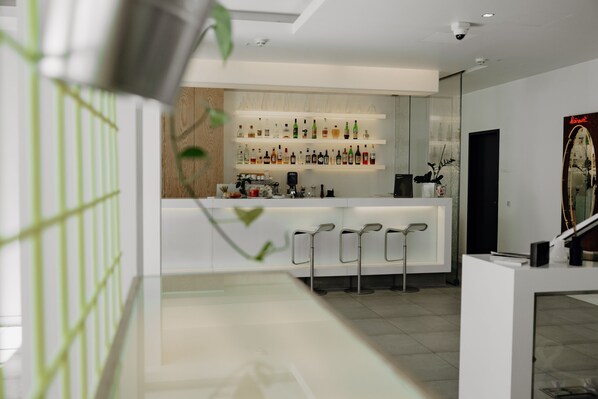 Un espace bar moderne avec des étagères remplies de bouteilles d’alcool, un comptoir et des tabourets de bar.