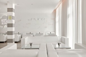 A modern, minimalist hotel lobby with white furniture and a large wall with handwritten notes.