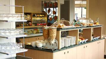 Montaje de bufé con diversos alimentos, fuentes de servicio y cristalería.