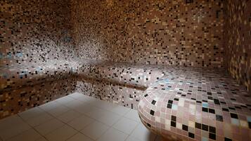 A room with a mosaic tiled wall, a bench, and a tiled floor.