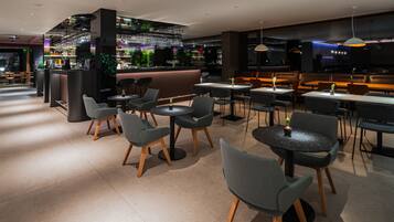 Um restaurante moderno com área de bar, diferentes opções de assentos e iluminação ambiente.