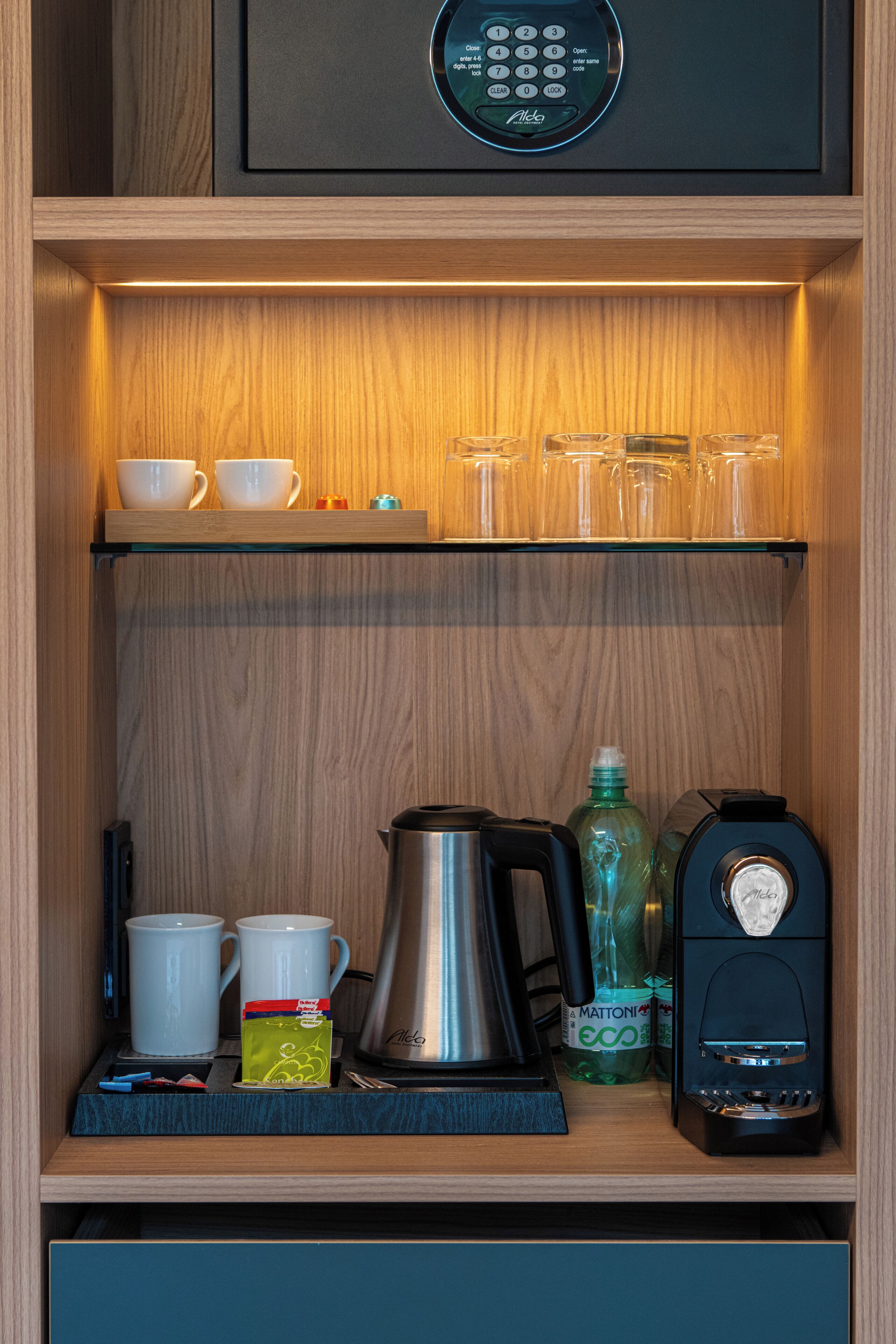 A kitchen area with a coffee maker, a kettle, and a bottle of water on the counter.