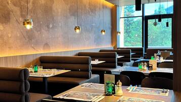 Un interior de restaurante moderno con asientos tipo cabina, mesas con menús e iluminación colgante.