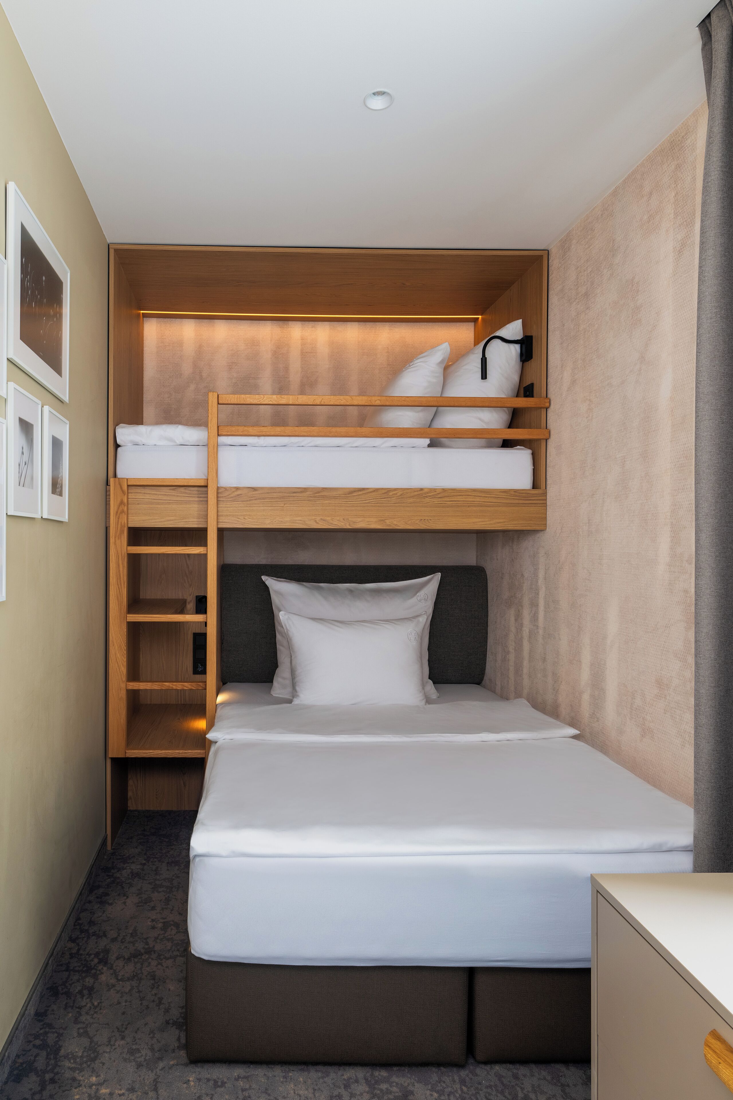 Ein kleines Hotelzimmer mit Etagenbett, Schreibtisch und einer gemütlichen Sitzecke.