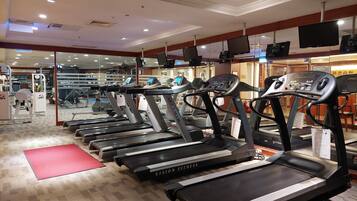 A gym with multiple treadmills, exercise equipment, and a mirrored wall.