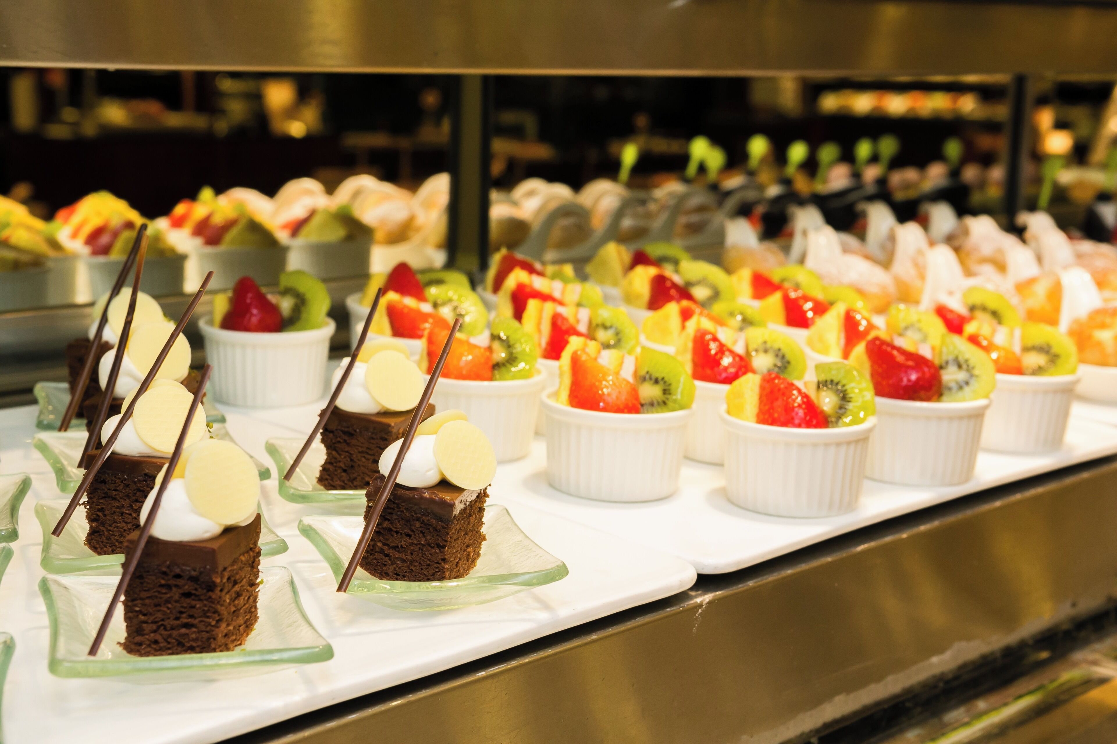 A buffet with various desserts and fruit cups.