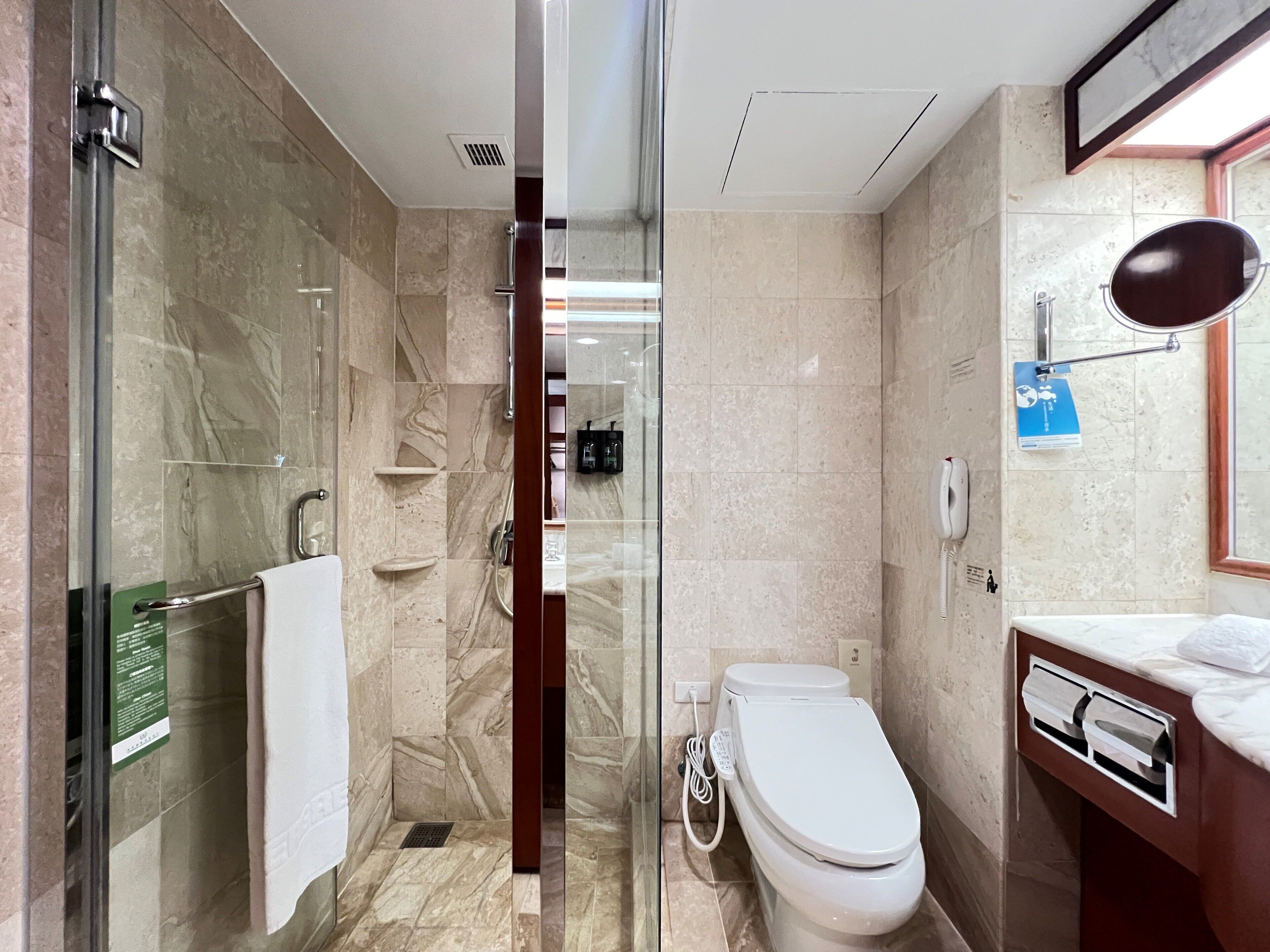 Un baño moderno con cabina de ducha de vidrio, inodoro y tocador con espejo.
