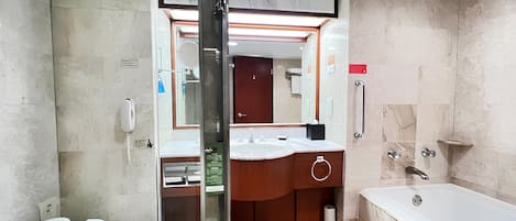 A modern bathroom with a toilet, sink, mirror, and bathtub.