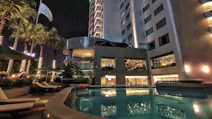 Een hotel met een zwembad, palmbomen en vlaggen.