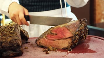 A person slicing a large piece of meat on a cutting board.