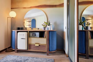 A modern bathroom with a vanity, a mirror, a small refrigerator, and a floor lamp. - Hotel Val di Sogno (Malcesine)