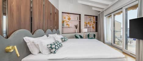 Un dormitorio moderno con una cama grande, paneles de madera, televisor y vistas al balcón.