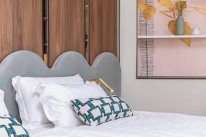 A neatly made bed with white linens and a patterned pillow, a bedside lamp, and a wooden wardrobe in the background. - Hotel Val di Sogno (Malcesine)