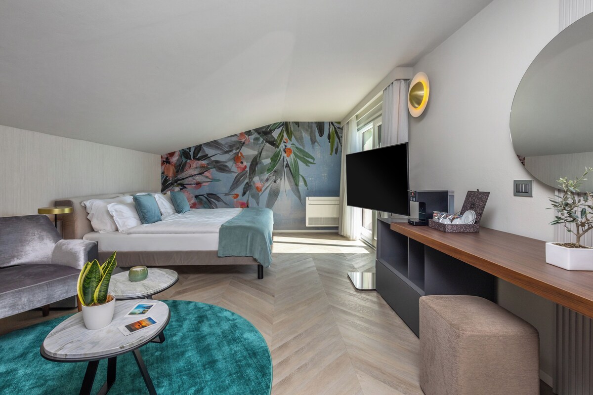 Un dormitorio moderno con una cama, un sofá, un televisor y un escritorio con una planta.