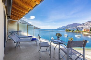 A balcony with a view of the sea, a table with a plant, and two lounge chairs. - Hotel Val di Sogno (Malcesine)