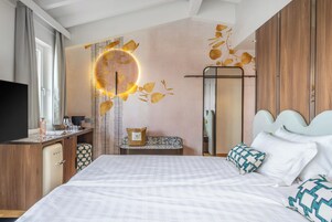 Una habitación de hotel moderna con una cama, un escritorio, un espejo y una lámpara circular en la pared.