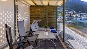 A terrace with outdoor seating, a small table with a plant, and a view of a coastal town. - Hotel Val di Sogno (Malcesine)