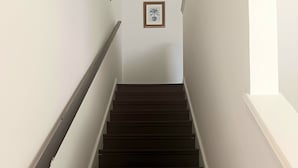 A staircase with dark steps and white walls, leading to a landing with a framed picture. - The Cozy Inn (St. Augustine)